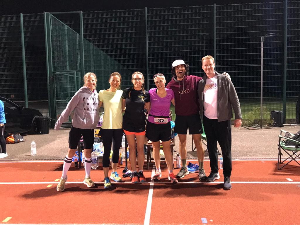 A group of people, including Ultra Runner Sinead Kane, posing for a photo on a race track