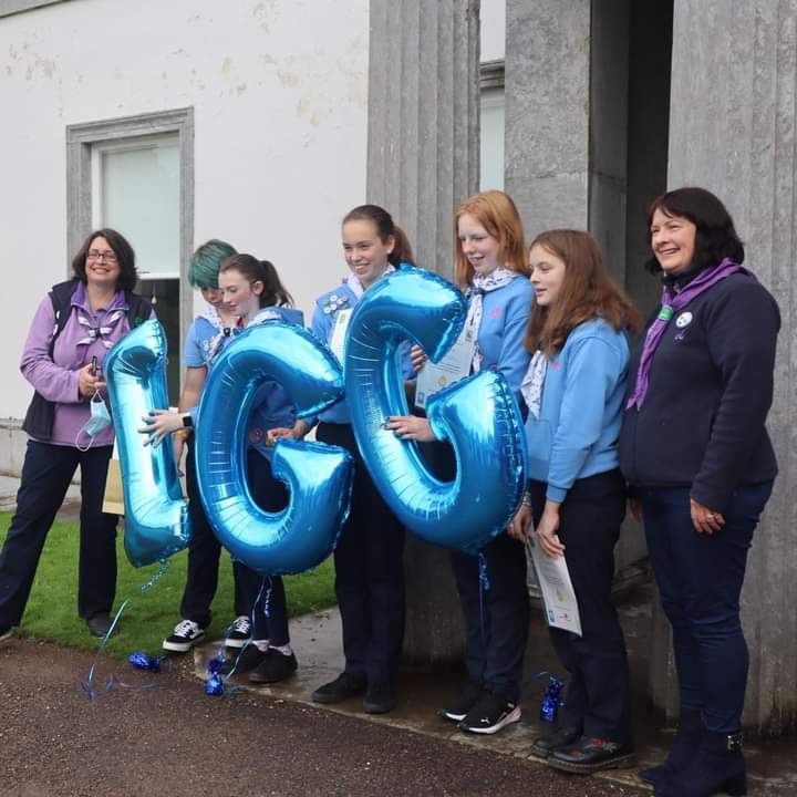 A group of girl guides holding balloons that spell out IGG