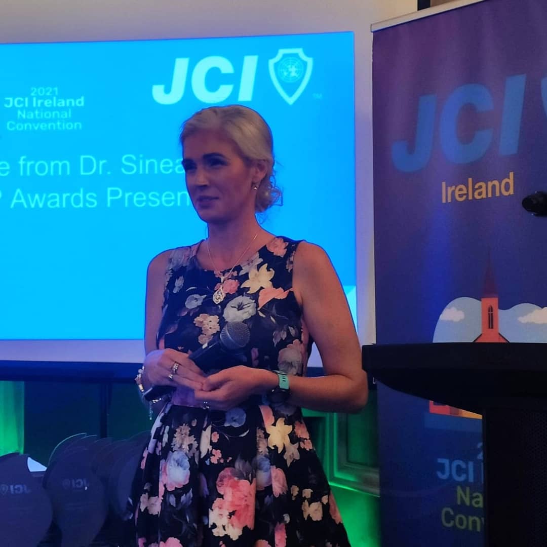 Motivational speaker Sinead Kane stood beside a lectern holding a microphone
