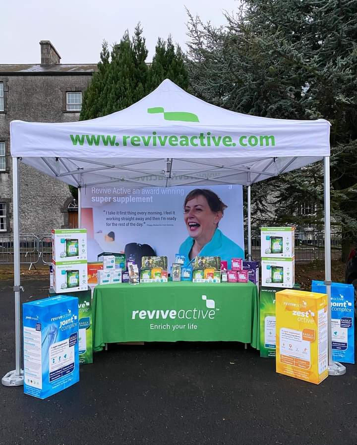 A Revive Active stand with a selection of their products on a table under a gazebo