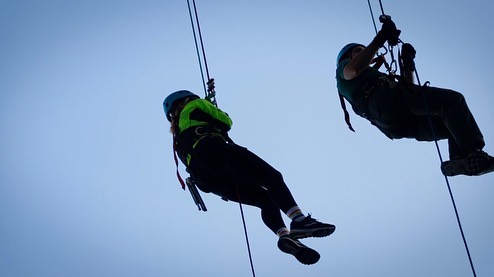 Sinead and John abseiling down the ropes. Sinead has an illuminous jacket on and blue helmet.