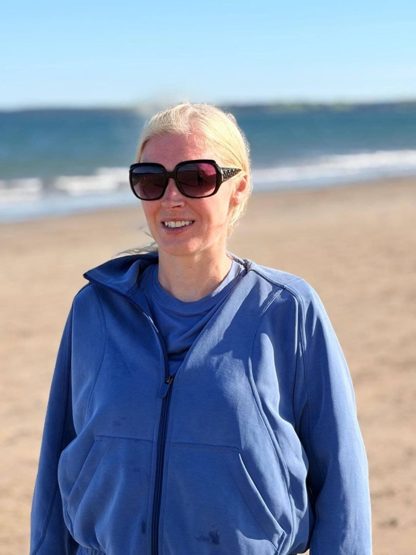 Sinead standing on Youghal beach wearing her own sunglasses.